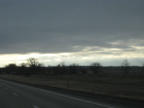 1978 Ford Bronco - View of a rural landscape under a cloudy sky, taken from a moving vehicle.