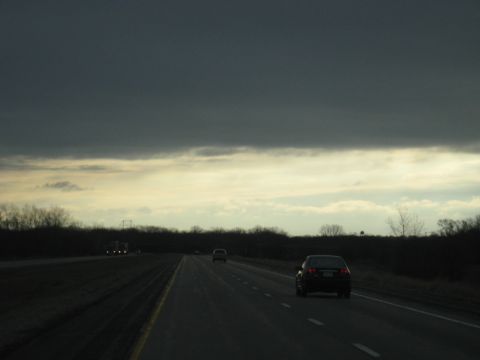 1978 Ford Bronco - Vehicles travel down a highway as storm clouds gather overhead.