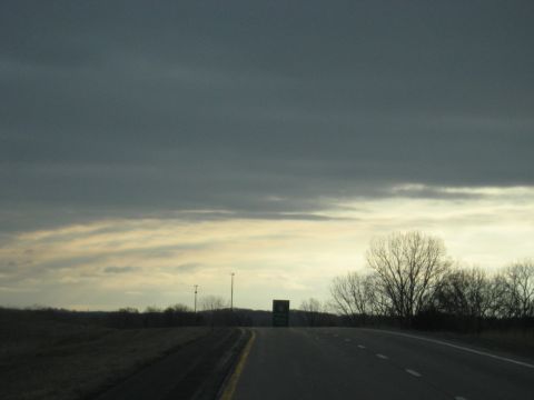 1978 Ford Bronco - A road sign is visible on the side of a highway as clouds gather overhead.