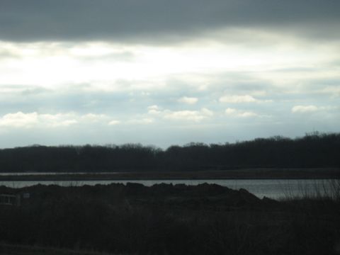 1978 Ford Bronco - A dark, overcast sky looms over a silhouetted landscape with a calm body of water in the distance.