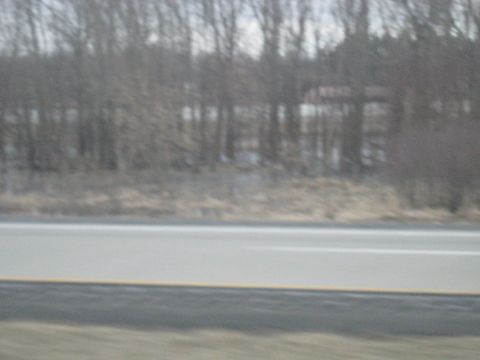 1978 Ford Bronco - A blurry view of a roadside scene, possibly from a moving vehicle on a highway.