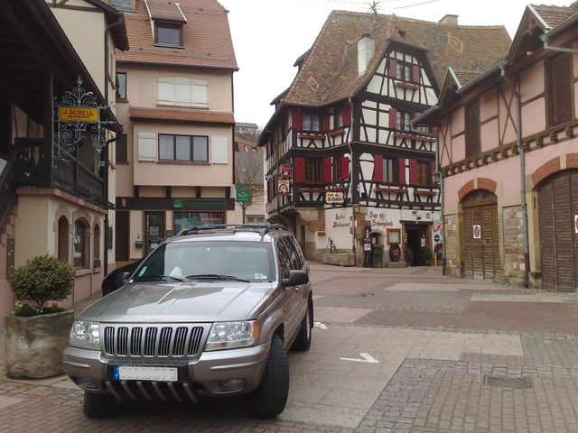 Silver Jeep Grand Cherokee parked on cobblestone street in front of half-timbered buildings