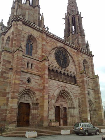 1991 Ford LTD Crown Victoria - A silver minivan is parked in front of a large, ornate stone cathedral.