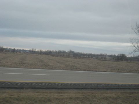 1978 Ford Bronco - A view of a road and a barren field under an overcast sky.
