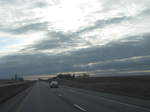 1978 Ford Bronco - Driving on a highway with a vast, cloudy sky overhead and other vehicles on the road.