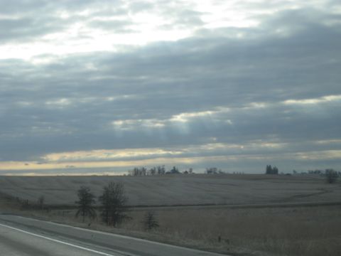 1978 Ford Bronco - Sunbeams break through clouds over a rural landscape with a road in the foreground.