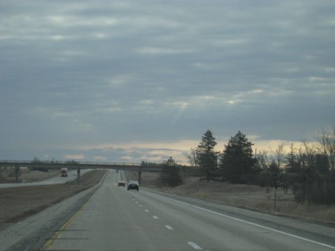 1978 Ford Bronco - A view from a vehicle traveling on a highway under a cloudy sky, with an overpass visible in the distance.