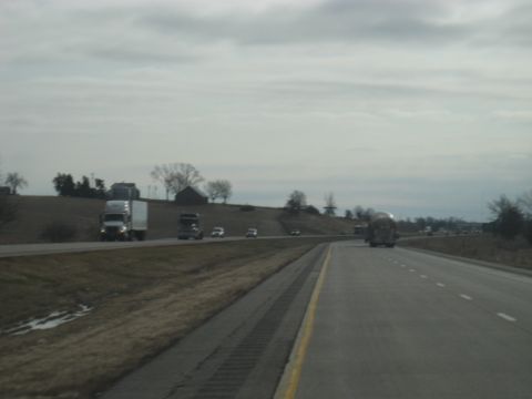 1978 Ford Bronco - Multiple vehicles travel along a highway on an overcast day, with rural landscape visible on the side.