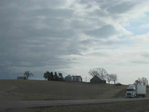 1978 Ford Bronco - A semi-truck travels down the highway near a farm on a cloudy day.