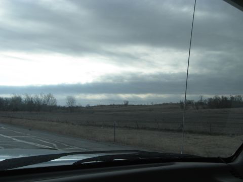 1978 Ford Bronco - View from inside a vehicle shows a desolate rural landscape under a cloudy sky.