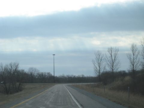 1978 Ford Bronco - A lonely stretch of highway under a gray, overcast sky with bare trees lining the roadside.