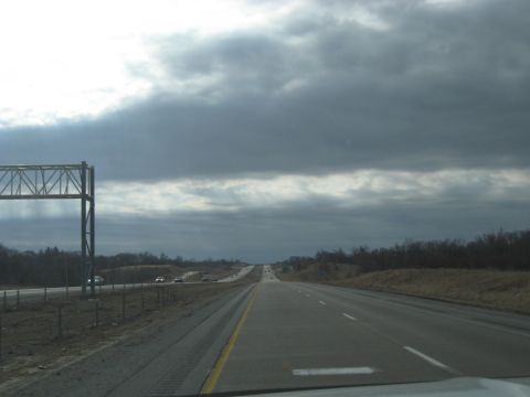 1978 Ford Bronco - A highway stretches into the distance under a heavily clouded sky, with a few vehicles visible on the road.