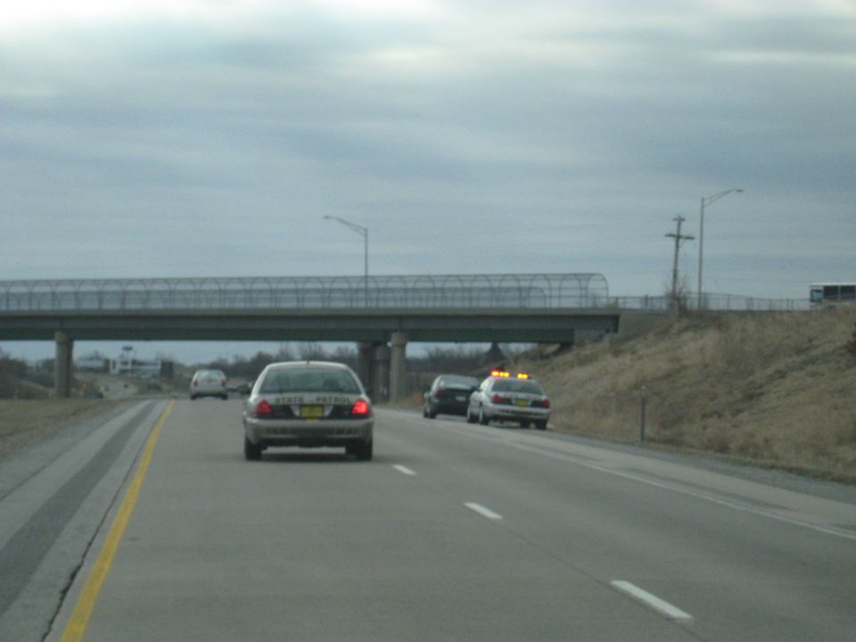 Cars on a highway under an overpass, with two police cars visible