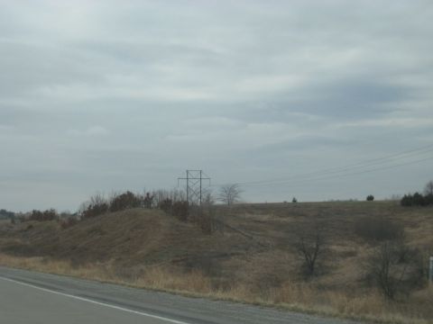 1978 Ford Bronco - A transmission tower stands on a hill under a cloudy sky, with power lines stretching across the frame.