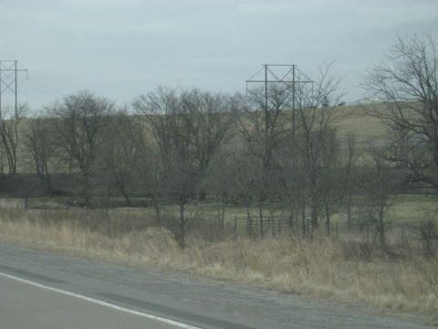 1978 Ford Bronco - A desolate rural scene under an overcast sky, with power lines stretching across the horizon.
