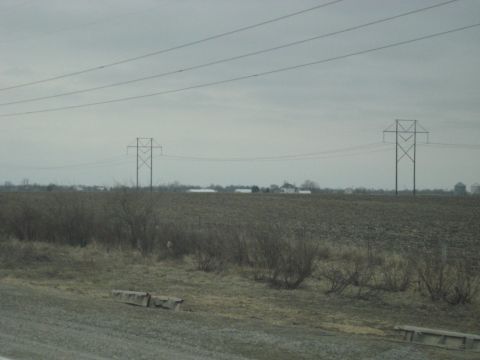 1978 Ford Bronco - A rural landscape is depicted under an overcast sky, with power lines dominating the upper frame.