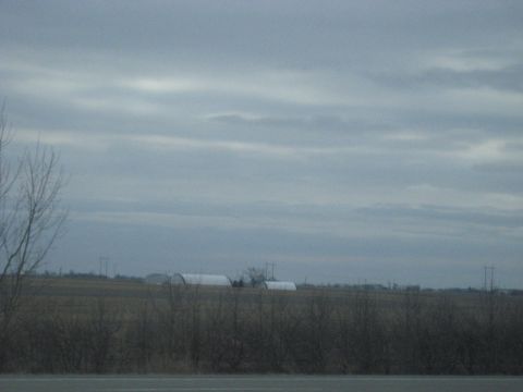 1978 Ford Bronco - A cloudy day over a rural landscape quonset huts in the distance.