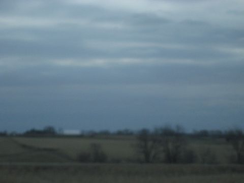1978 Ford Bronco - A wide shot of a rural landscape under a cloudy sky, with no vehicles visible.