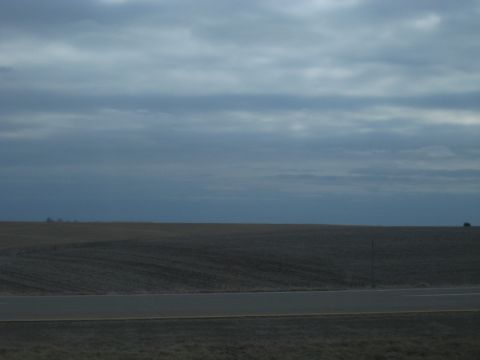 1978 Ford Bronco - A lone dark SUV is visible on a distant hill under a vast, cloudy sky.