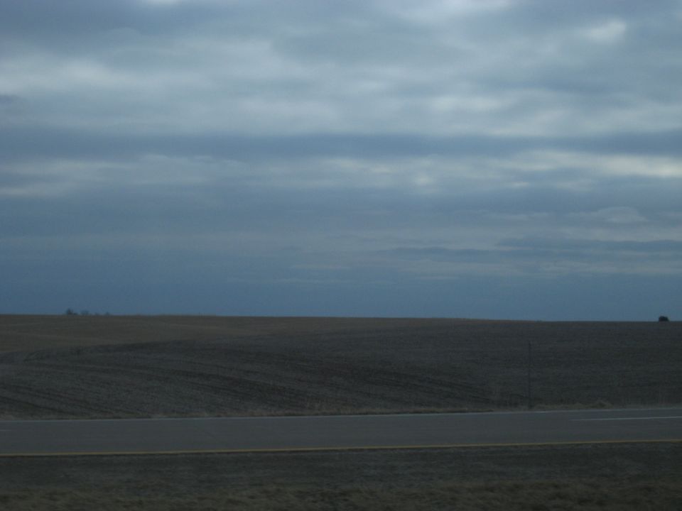 Dark SUV on a distant hill under a cloudy sky