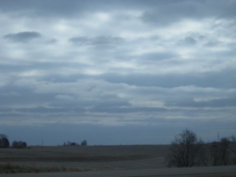 1978 Ford Bronco - A cloudy sky looms over a rural landscape with bare trees.