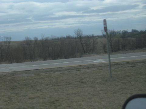 1978 Ford Bronco - A solitary roadside sign stands against a backdrop of bare trees and a cloudy sky, suggesting a rural or highway setting.