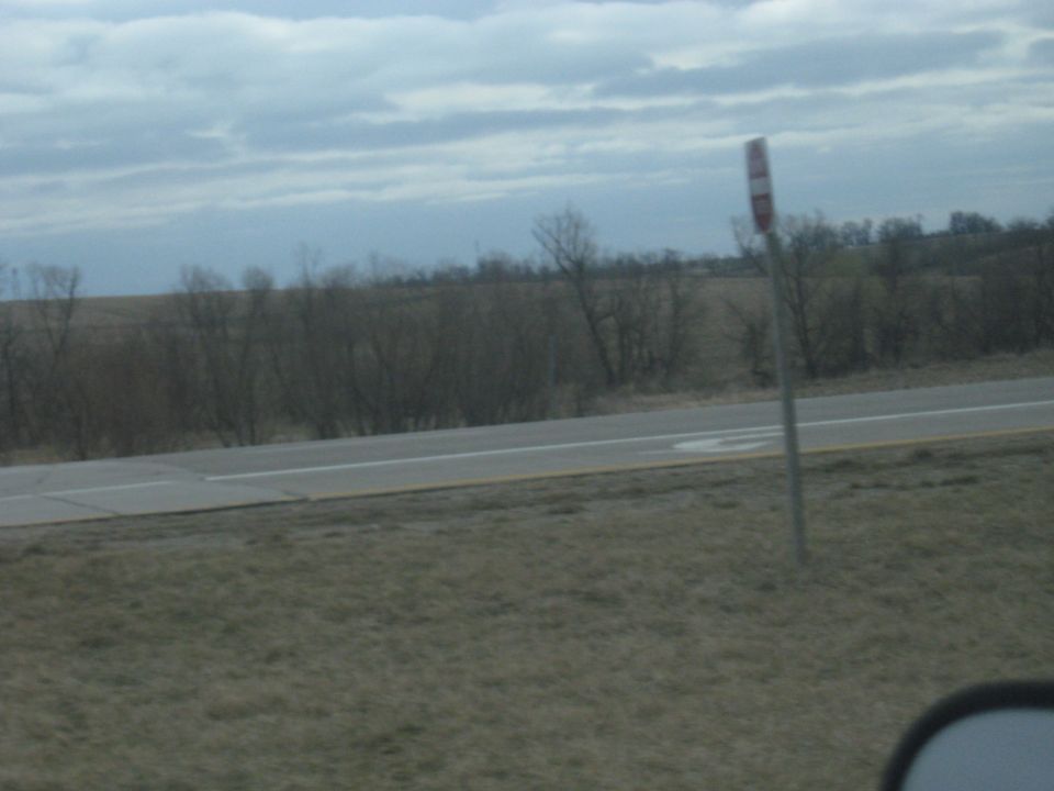 Roadside sign with red and white stripes against a cloudy sky