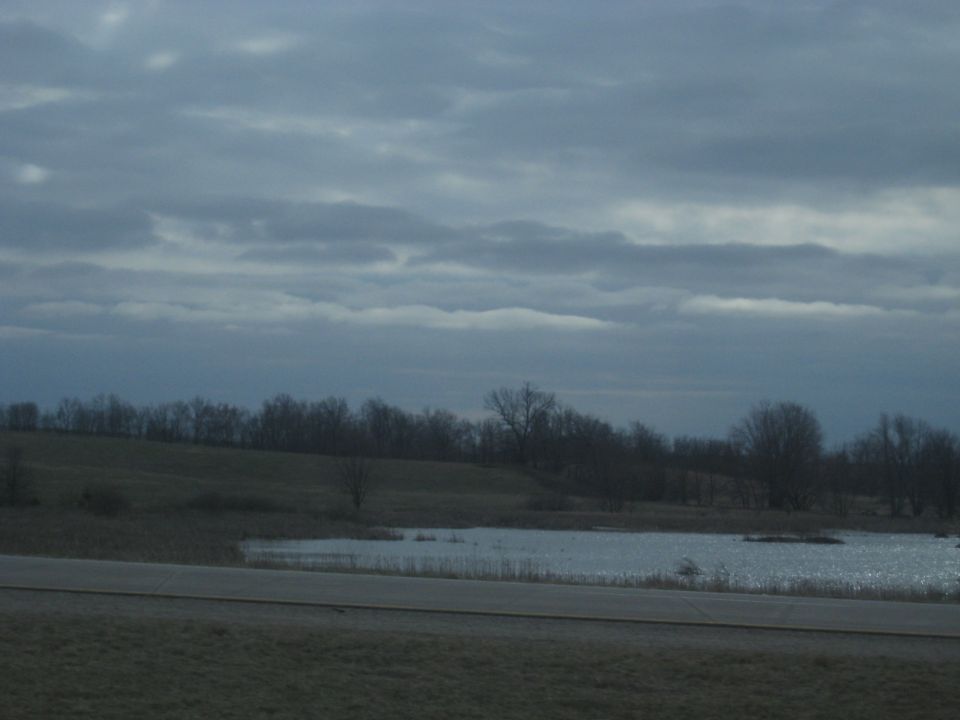 cloudy sky over a body of water and treeline
