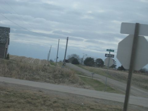 1978 Ford Bronco - A rural intersection features a stop sign and a one-way sign, with a barn and fields visible under an overcast sky.