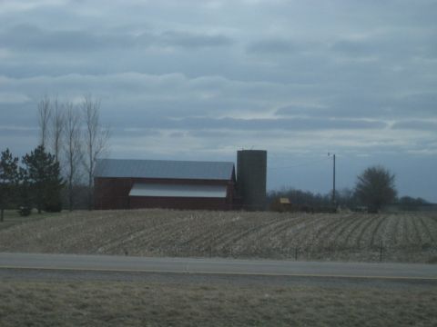 1978 Ford Bronco - A rural landscape features a red barn, a tall silo, and a field of dried corn stalks.