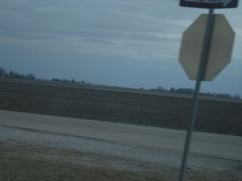 1978 Ford Bronco - A rural landscape unfolds under a muted sky, with traffic signs marking the edge of the road.