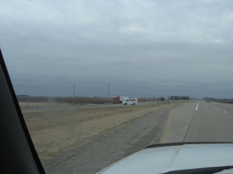 1978 Ford Bronco - A FedEx truck and a semi-truck travel down a highway on an overcast day.