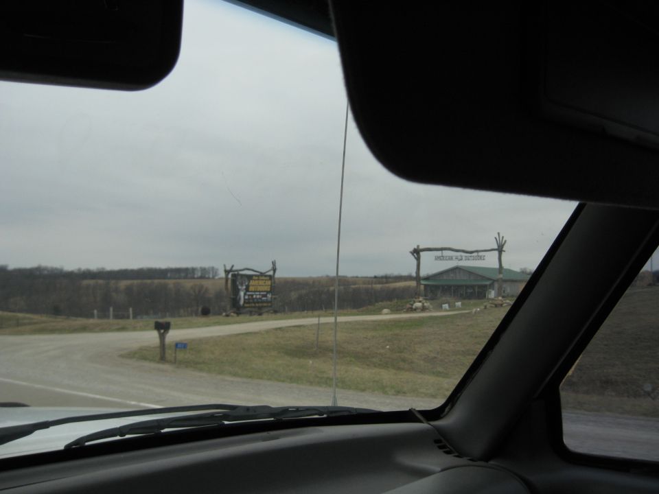 View from inside a vehicle looking out at a building with a wooden archway and a large billboard sign