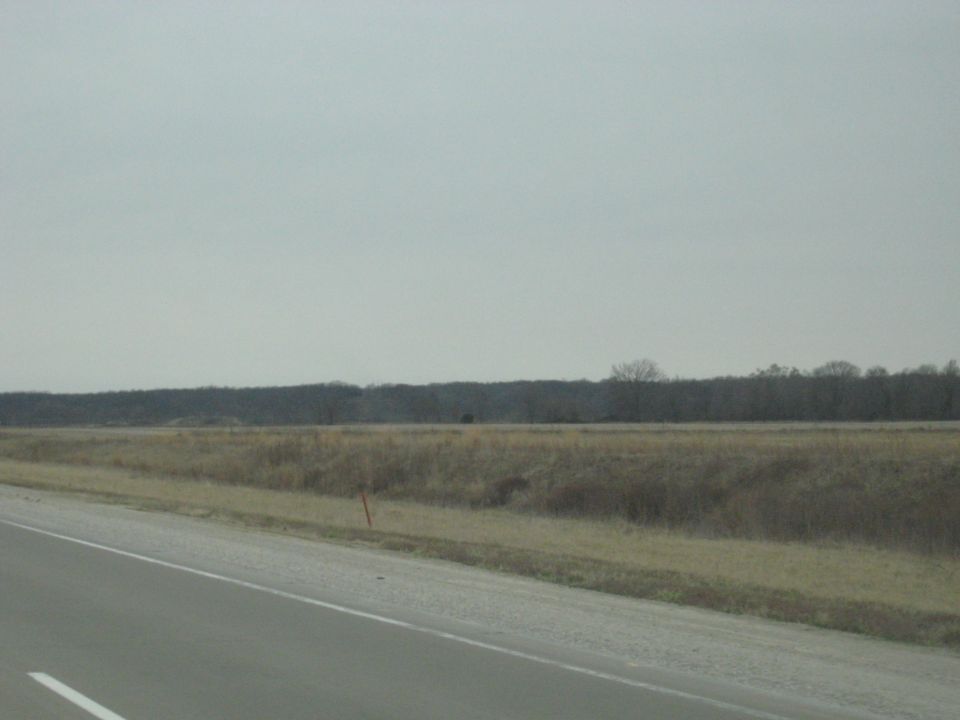 Overcast sky above a rural landscape with a road in the foreground and a distant tree line