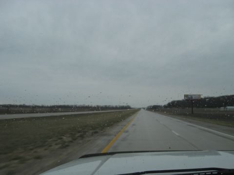 1978 Ford Bronco - Driving on a wet highway with raindrops on the windshield under an overcast sky.