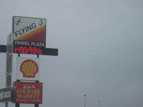 1978 Ford Bronco - A sign for a Flying J Travel Plaza indicates propane availability, with Shell and Country Market logos visible.