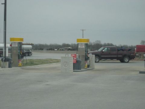 1978 Ford Bronco - A maroon pickup truck is parked at a gas station with an ATV loaded in its bed.