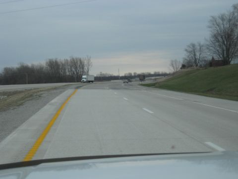 1978 Ford Bronco - A view from a vehicle driving on a highway with other vehicles present and trees lining the roadside.