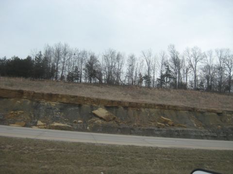 1978 Ford Bronco - A view of a geological formation alongside a road, with trees on the hill above.