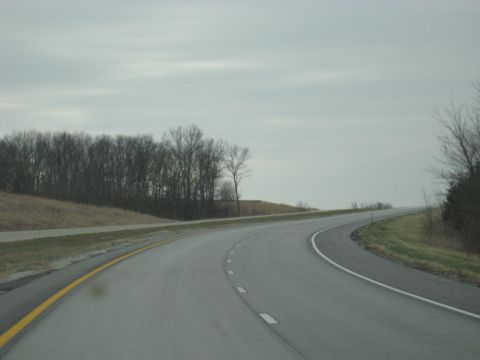 1978 Ford Bronco - A desolate highway stretches ahead under an overcast sky, bordered by bare trees and dry grass.