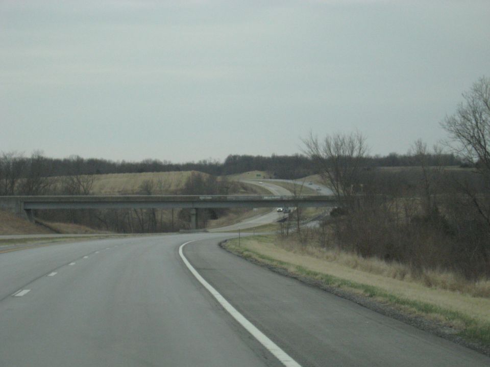 Highway overpass with a curved road in the foreground under an overcast sky