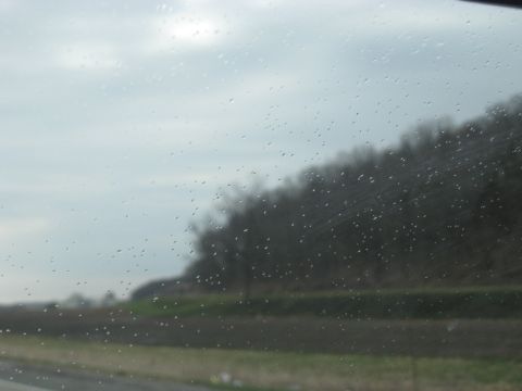 1978 Ford Bronco - View of a rural landscape through a rain-streaked car window on a cloudy day.