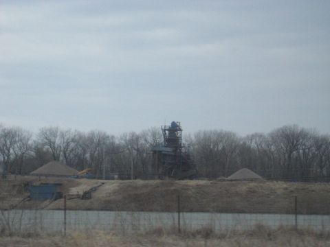 1978 Ford Bronco - A gravel processing plant is visible in the distance, surrounded by bare trees and piles of gravel.