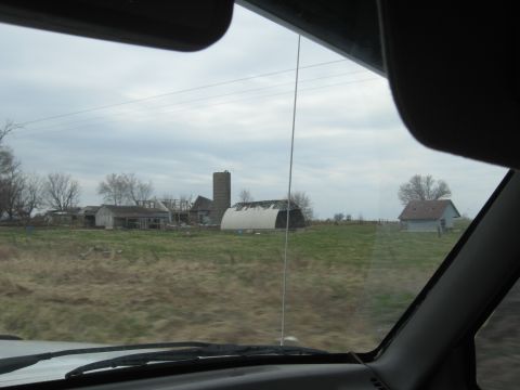 1978 Ford Bronco - A rural landscape unfolds with various farm structures and a tall silo under an overcast sky.