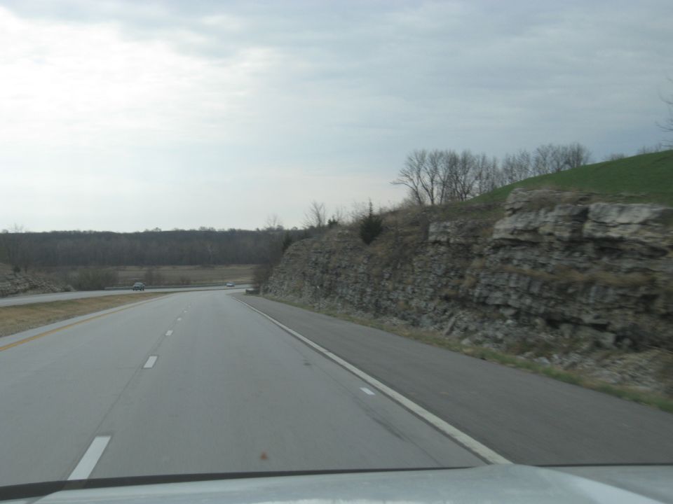 Highway driving scene with two cars visible in the distance under an overcast sky
