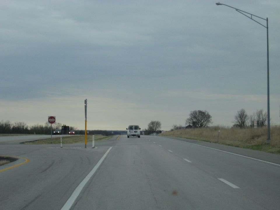 White van driving on a highway under a cloudy sky