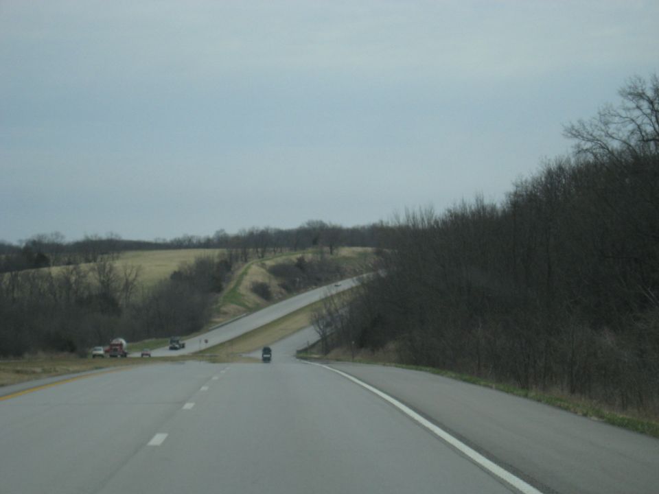 View from a car on a highway, with a few other vehicles visible on the road and shoulder