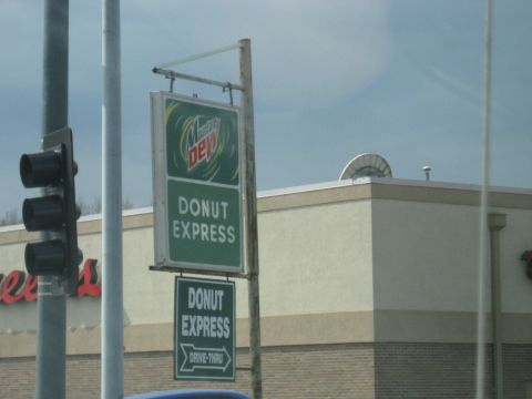 1978 Ford Bronco - A sign for Donut Express is visible next to a traffic light, with a building in the background.