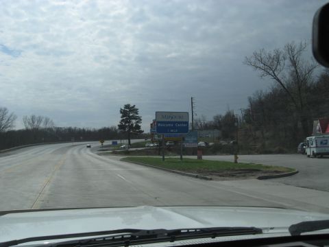 1978 Ford Bronco - Approaching the Missouri Welcome Center on a cloudy day, with a USPS truck visible.