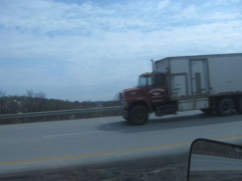 1978 Ford Bronco - A red semi-truck travels down the road under a cloudy sky.